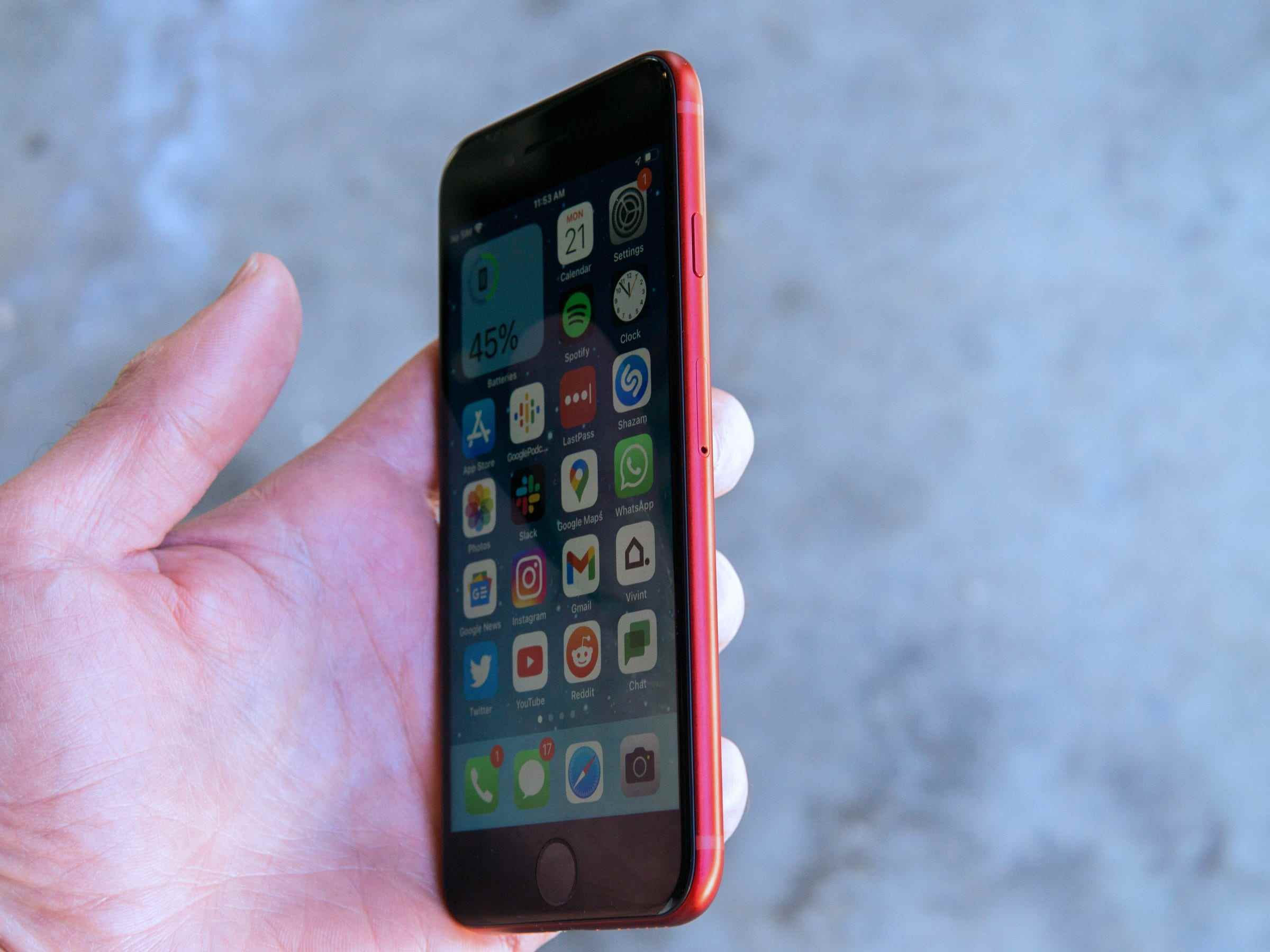 Das rote 2022 iPhone SE, das in der Hand des Autors gehalten wird, ist schräg geneigt, um die rechte Kante des Telefons zu zeigen.