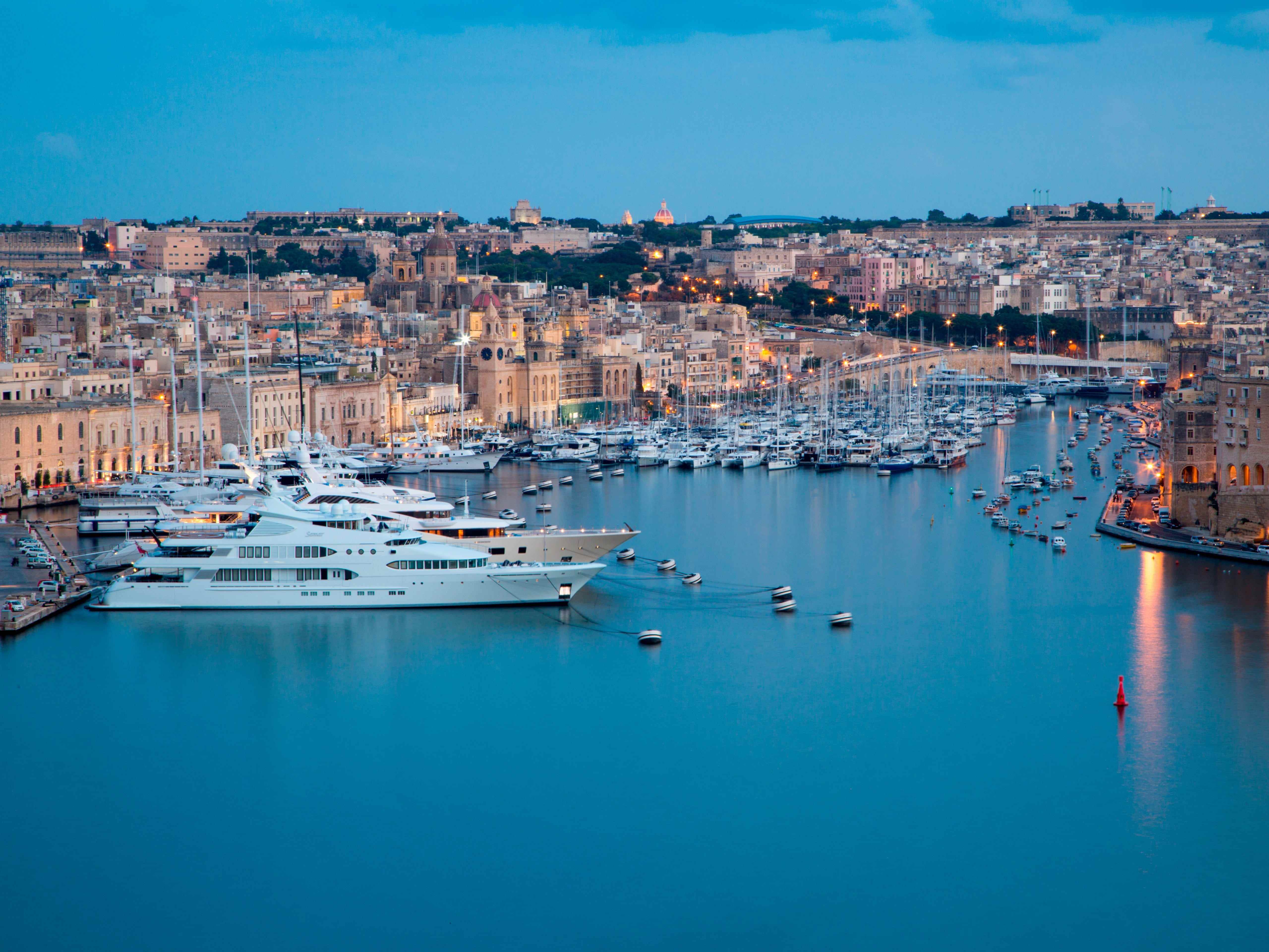 Luxusyachten und Segelboote in Kalkara Marina mit Vittoriosa auf der rechten Seite von Upper Barrakka Gardens in der Abenddämmerung, Valletta, Malta.