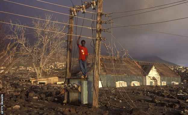 Zehn Jahre nach dem Ausbruch im Juli 1995 posiert ein Junge auf einer eingestürzten Strominfrastruktur