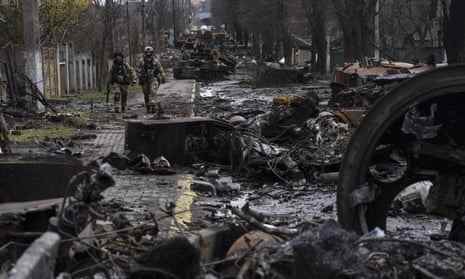 Soldaten gehen inmitten zerstörter russischer Panzer in Bucha am Stadtrand von Kiew, Ukraine.