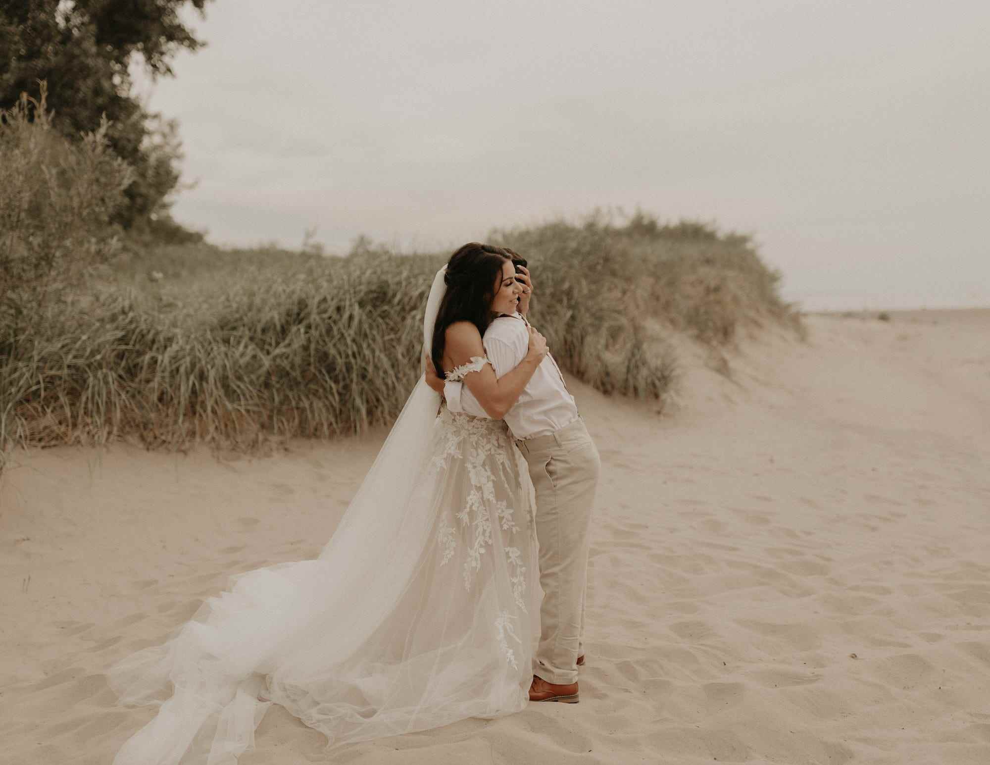 Eine Braut und ihr Bruder umarmen sich am Strand.