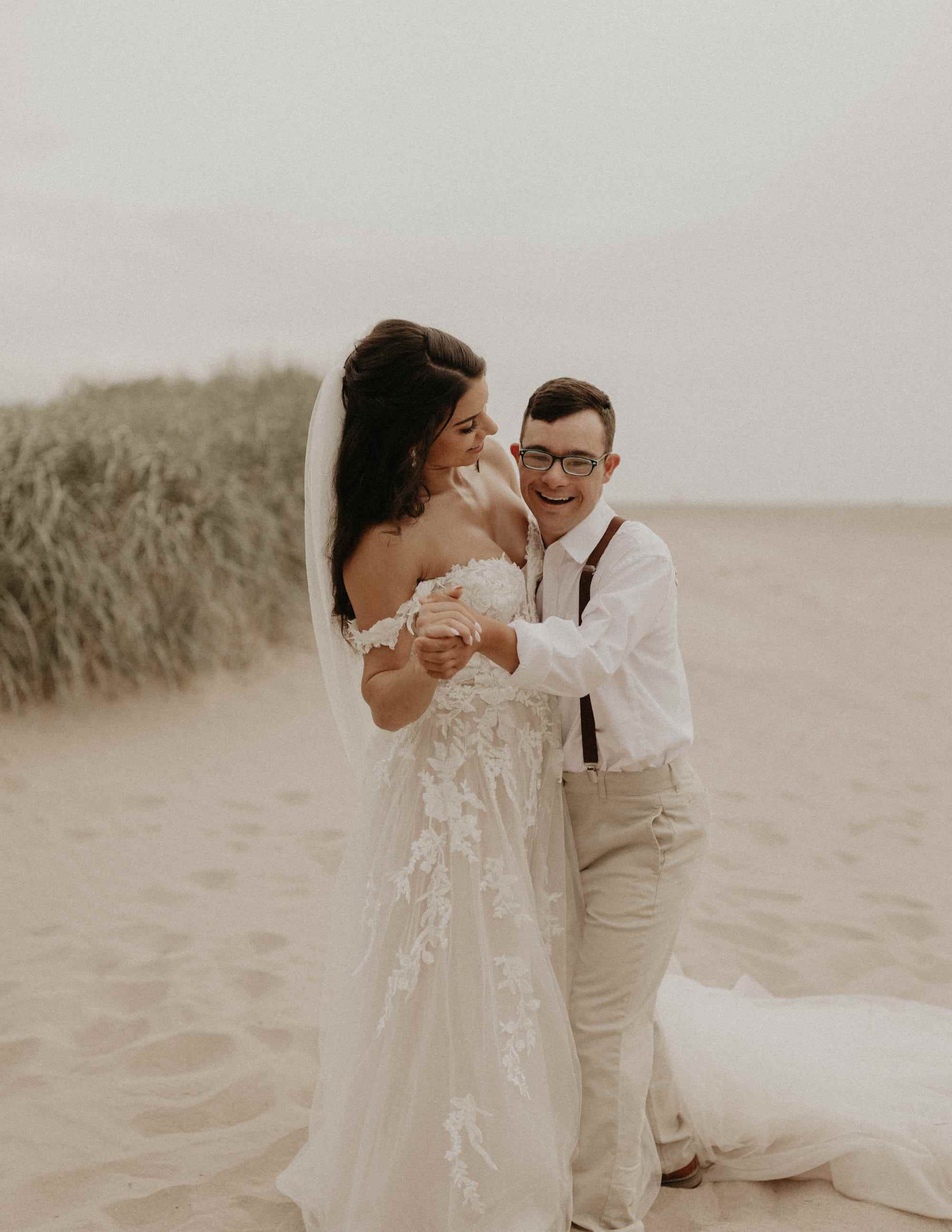 Eine Braut und ihr Bruder tanzen am Strand.