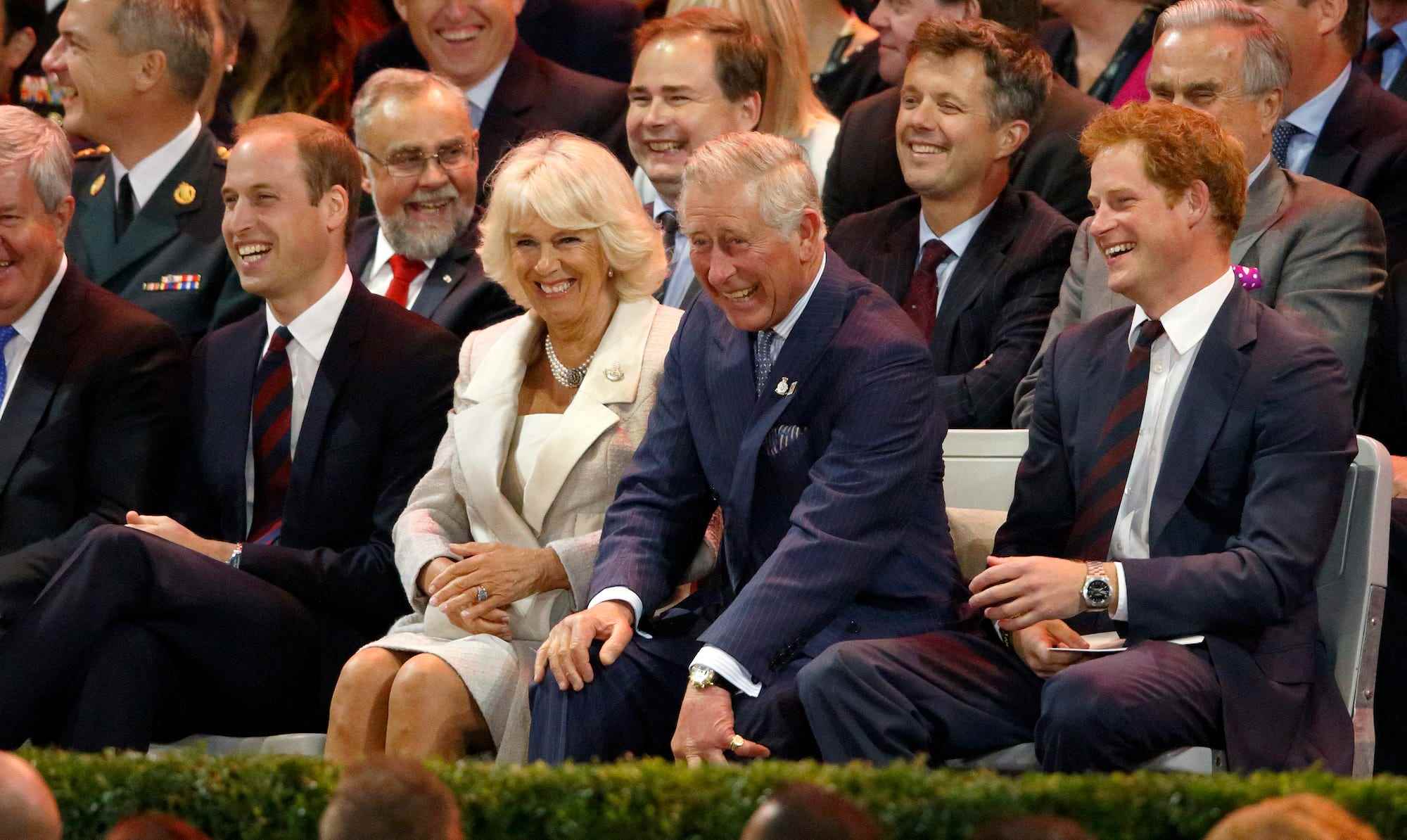 Prinz William, Camilla Parker Bowles, Prinz Charles und Prinz Harry sitzen in einer Menschenmenge.