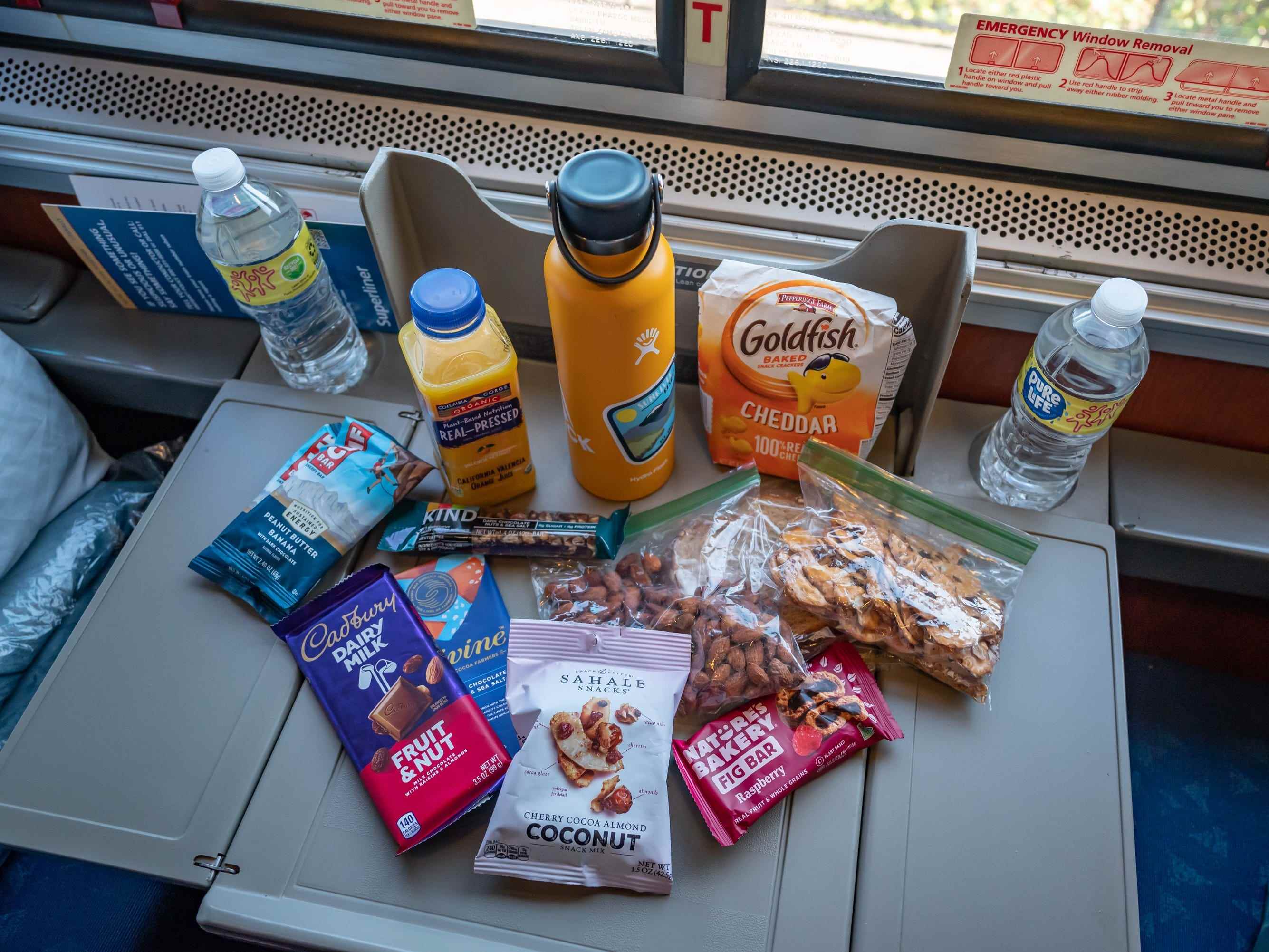 Ausziehbares Tablett bei Amtrak, gefüllt mit Wasserflaschen, Goldfisch-Crackern, Schokolade, Müsli, Brezeln und anderen vorverpackten Snacks