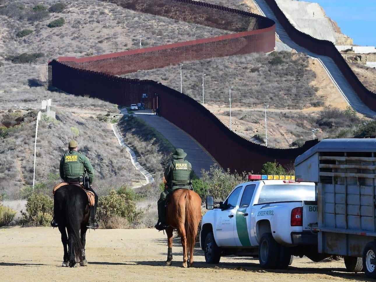 US-Grenzschutzbeamte auf Pferden in der Nähe des Zauns