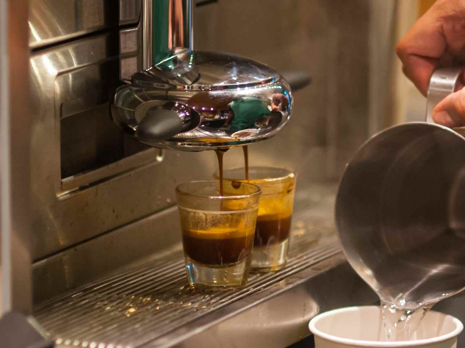 starbucks barista macht einen drink vor der espressomaschine mit zwei schüssen espress darauf