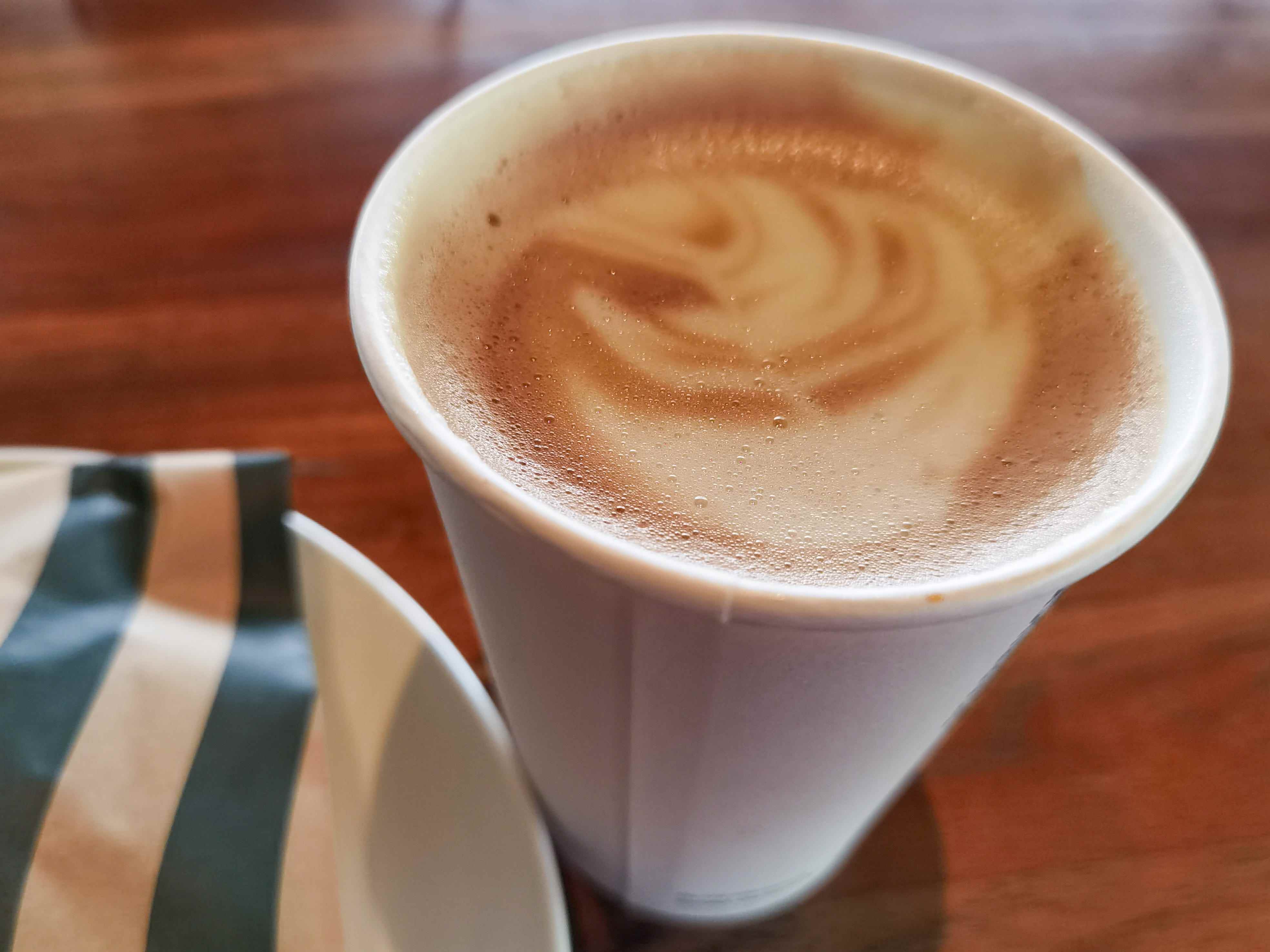 Cappuccino-Getränk von Starbucks mit Schaumkunst auf Zeit neben einem Spritzbeutel von Starbucks