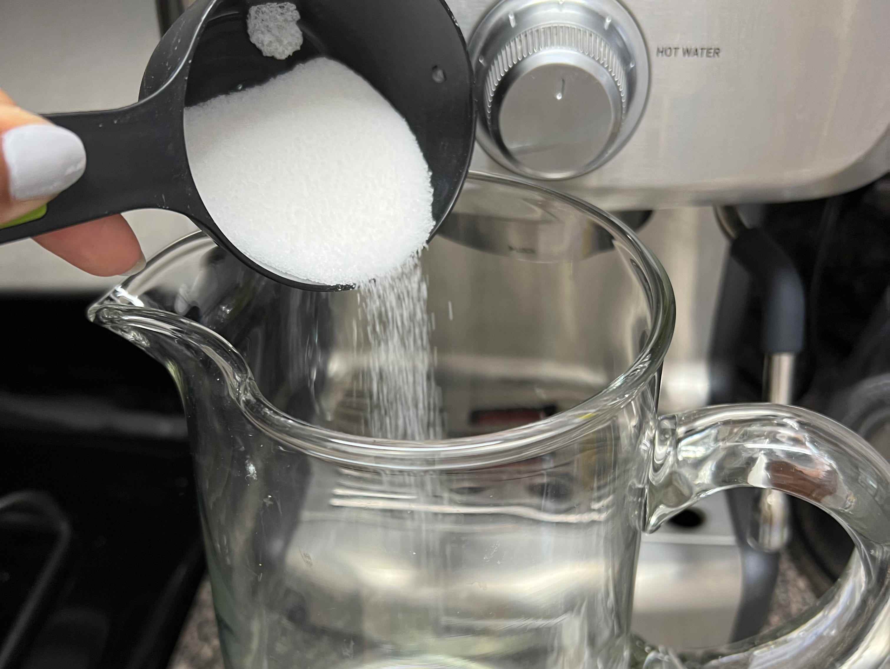 Für ein Jamaika-Rezept wird eine Tasse Zucker in einen Glaskrug gegossen.