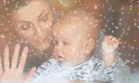 Eine Frau und ein Baby hinter einem Glasfenster bei Schneewetter.