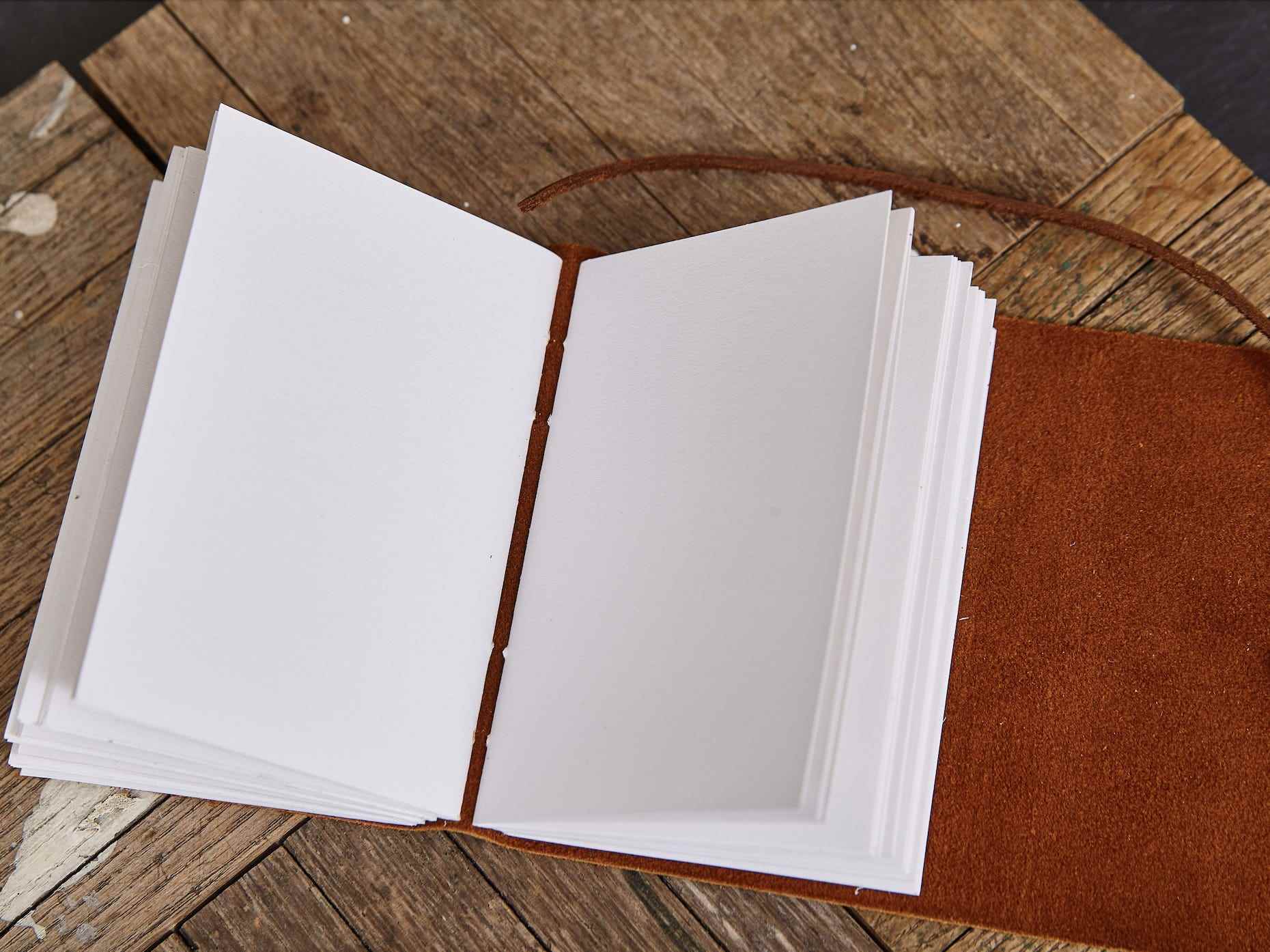 leeres ledergebundenes Tagebuch, das offen auf einer Holzoberfläche sitzt