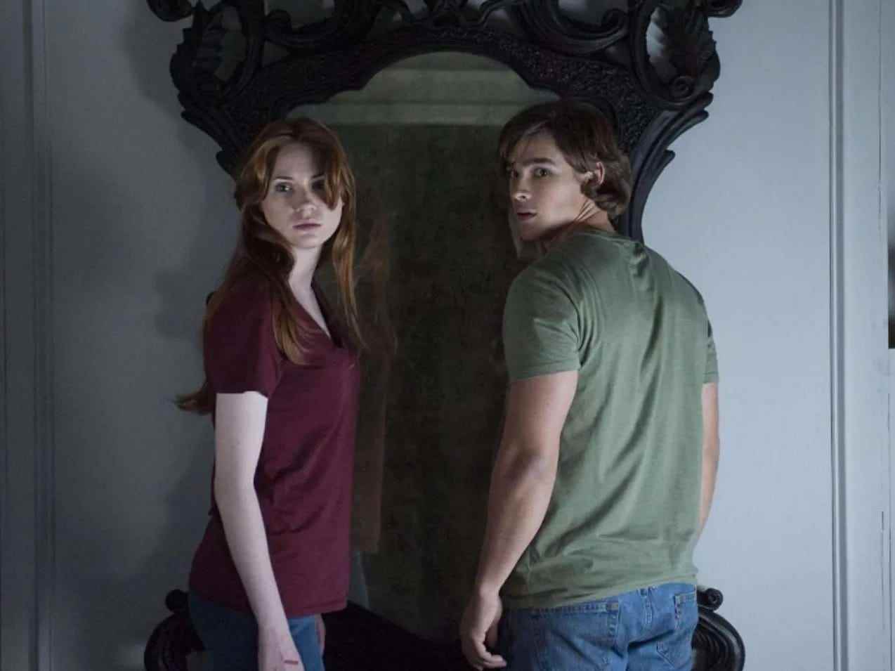 Ein Standbild aus dem Film „Oculus“ von zwei Charakteren, die vor einem Spiegel stehen.