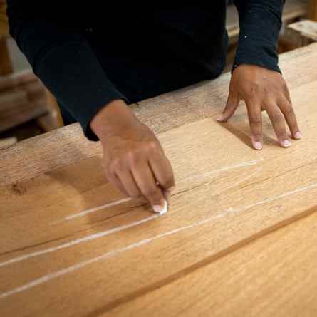 Eine Hand, die Kreidelinien auf ein Stück Holz zeichnet