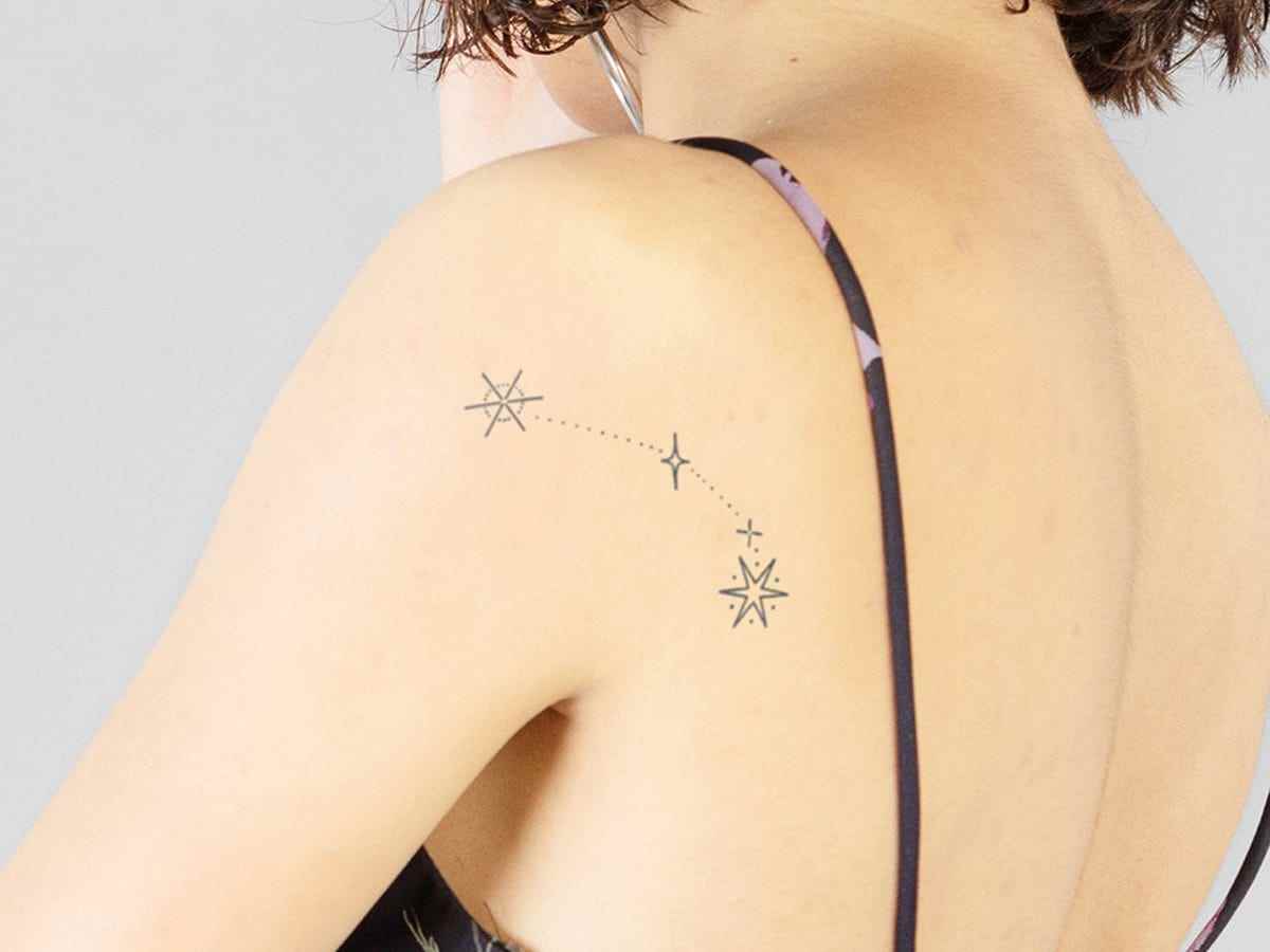 Der Rücken einer Person, geschmückt mit einem temporären Tattoo einer Widder-Konstellation auf ihrer Schulter.