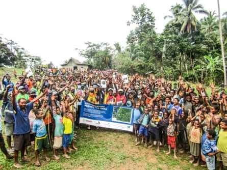 Mehrere hundert glücklich aussehende Menschen mit einem Banner, das ein neues Naturschutzgebiet verkündet