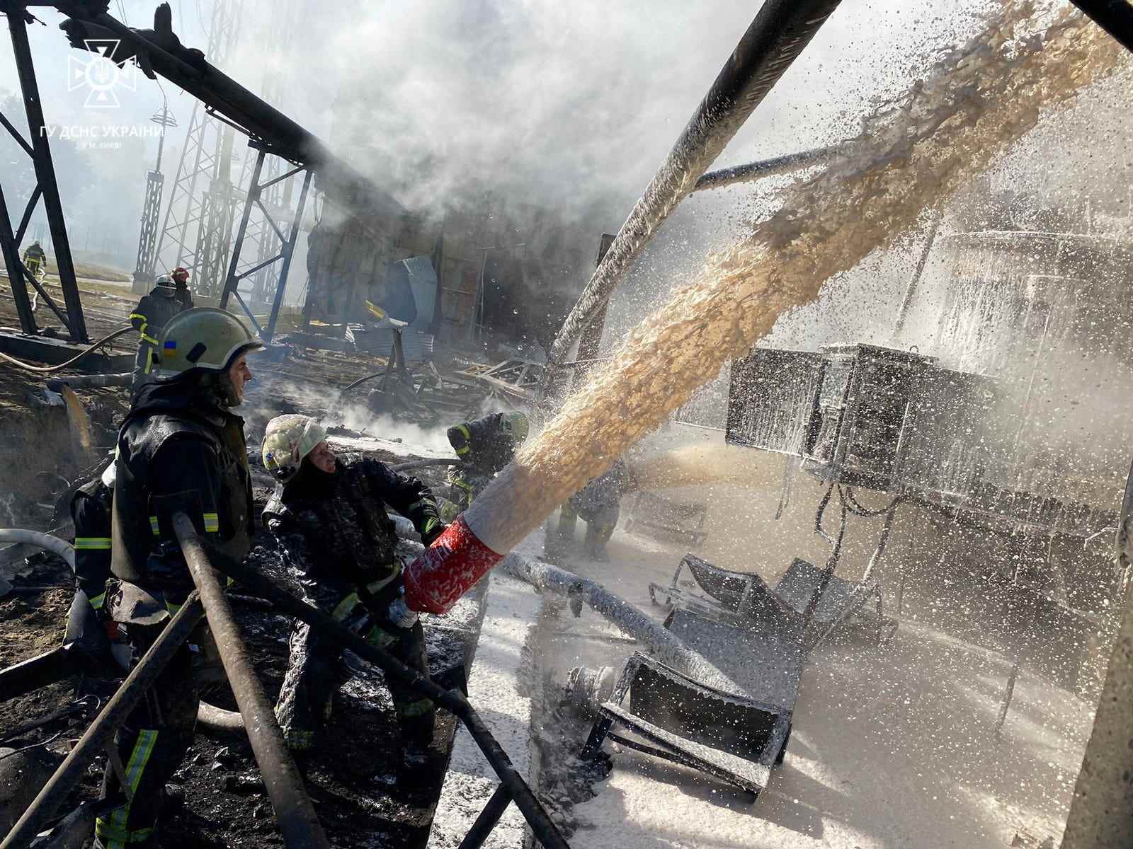 Feuerwehrleute spritzen ein Infrastrukturobjekt in Kiew, Ukraine, ab.
