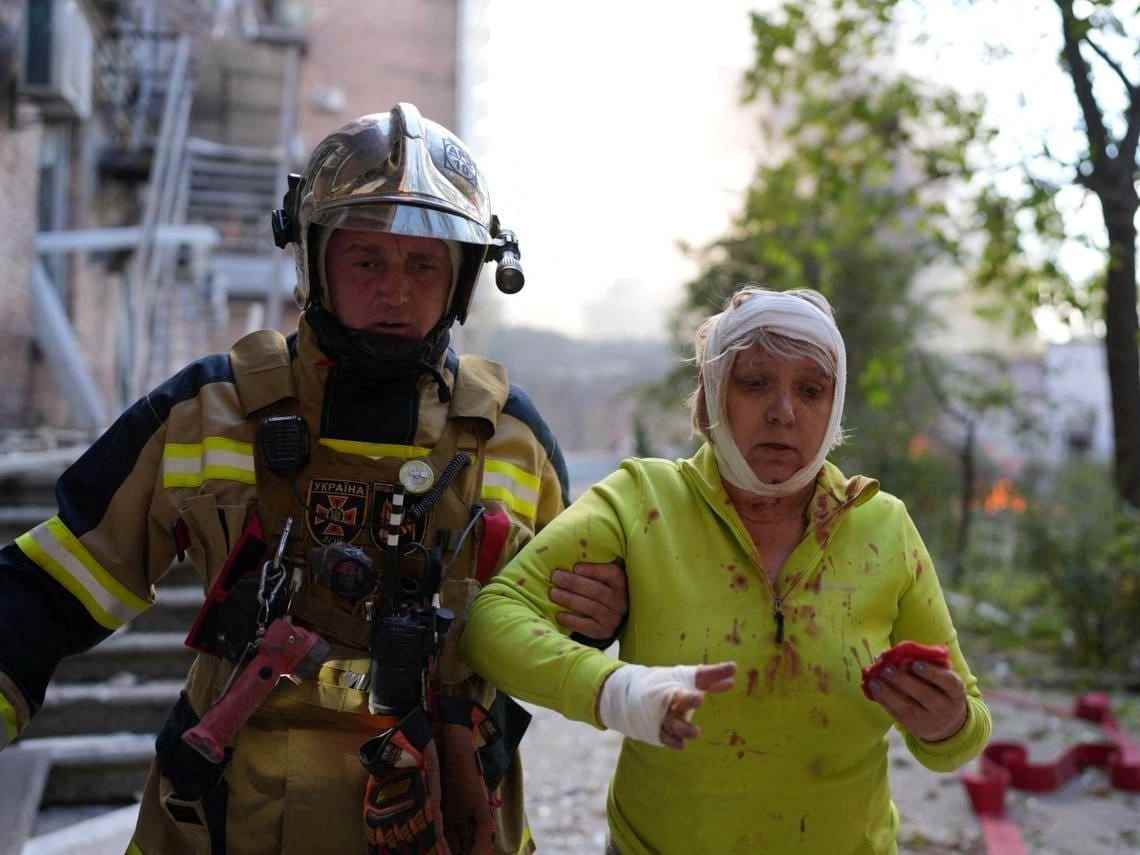 Retter hilft verletzter Frau in Kiew.