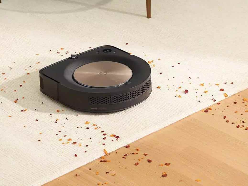 Der iRobot Roomba s9+ Saugroboter fegt ein Durcheinander auf einem Teppich.