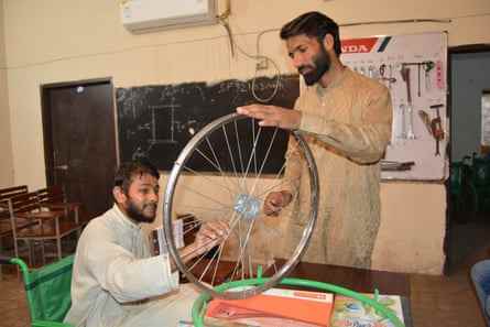 Usman Malik, links, wird von Muhammad Kashif in einem sechsmonatigen Schulungskurs einer Gesellschaft für besondere Personen darin unterrichtet, wie man Rollstühle baut.