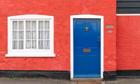 Ein farbenfrohes Häuschen in einem britischen Dorf mit roten Wänden und einer blauen Tür.