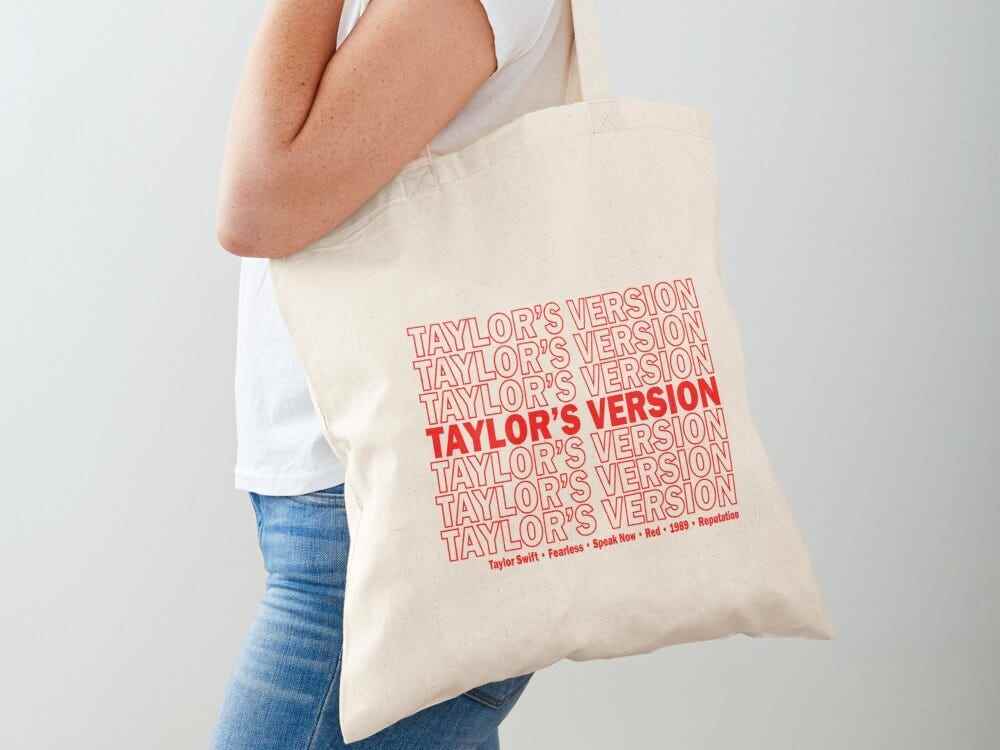 Person, die eine Leinentragetasche trägt, auf der „Taylor's Version“ in wiederholter roter Schrift steht