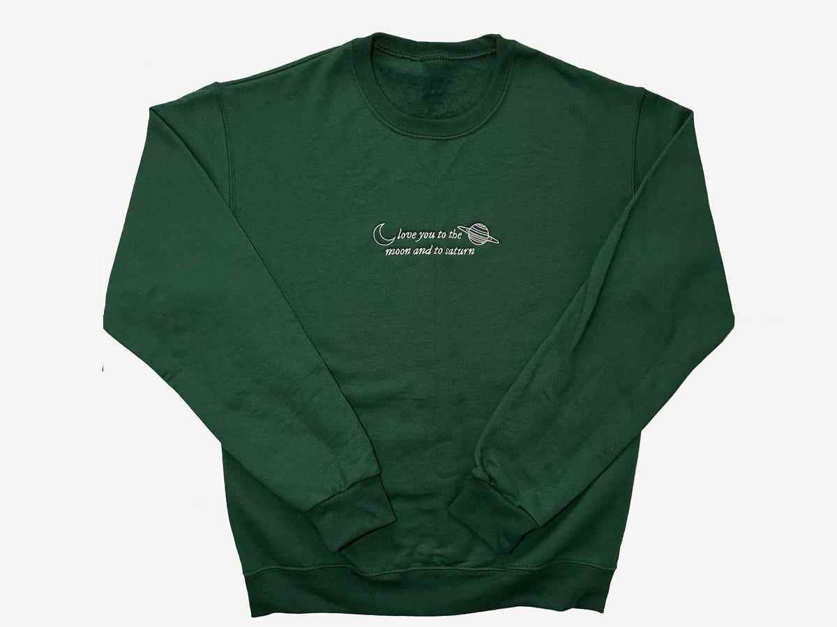 Ein waldgrünes Sweatshirt mit der Aufschrift „Love you to the moon and to Saturn“