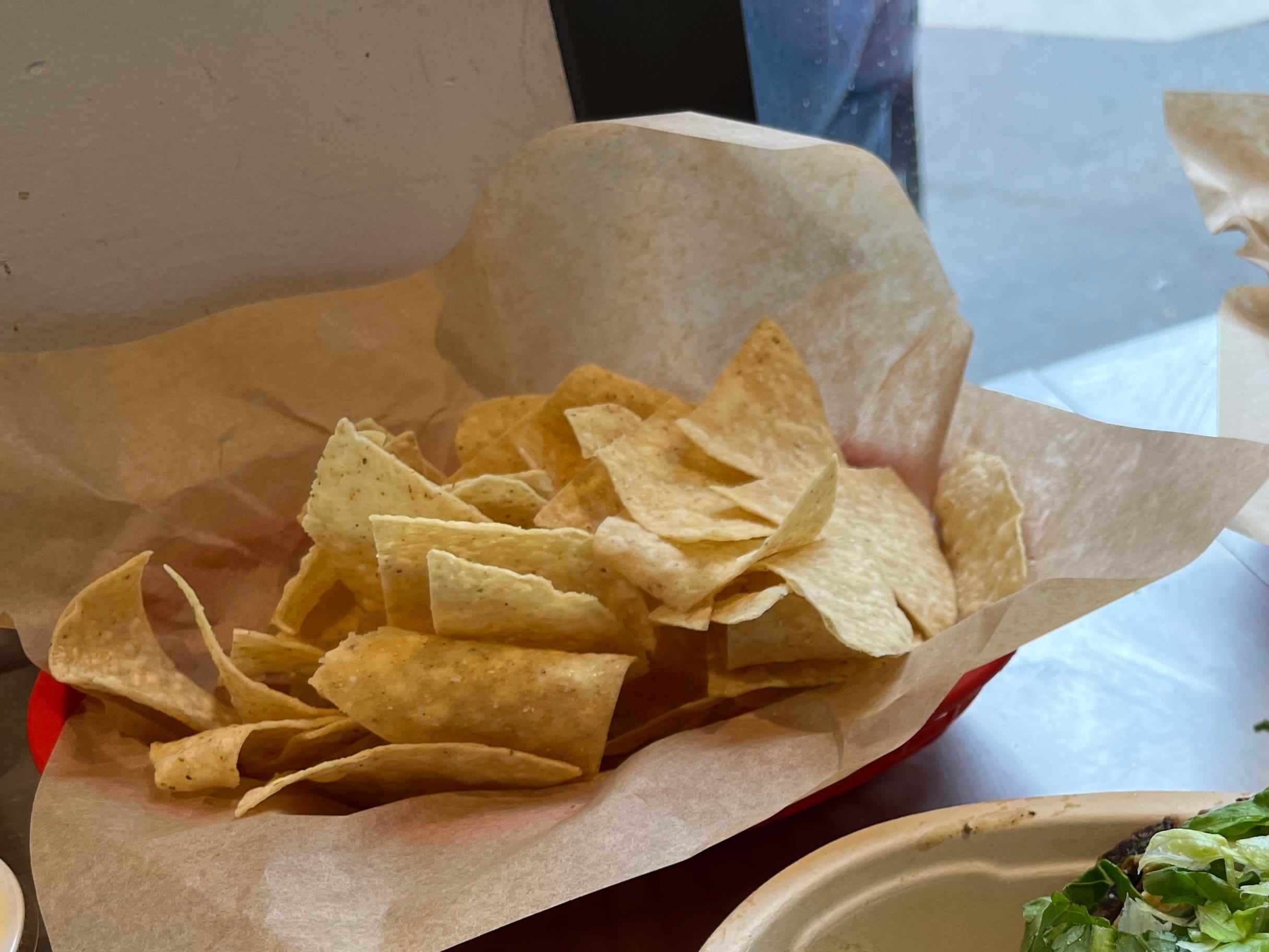Chips und eine Burrito-Schale von Chipotle auf einem Tisch am Fenster