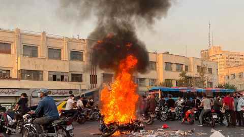 Menschen versammeln sich inmitten der Proteste am 8. Oktober neben einem brennenden Motorrad in Teheran.