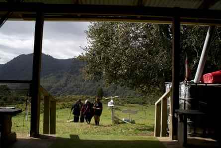 Blick von innen auf ein Haus, das drei Menschen zeigt, die einen Hügel hinaufgehen, mit einem Hubschrauber auf einer Koppel im Hintergrund