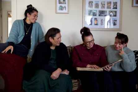 Vier Familienmitglieder betrachten ein Fotoalbum auf einer Couch