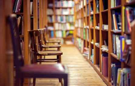 Bibliothek mit Büchern im Regal und leeren Stühlen