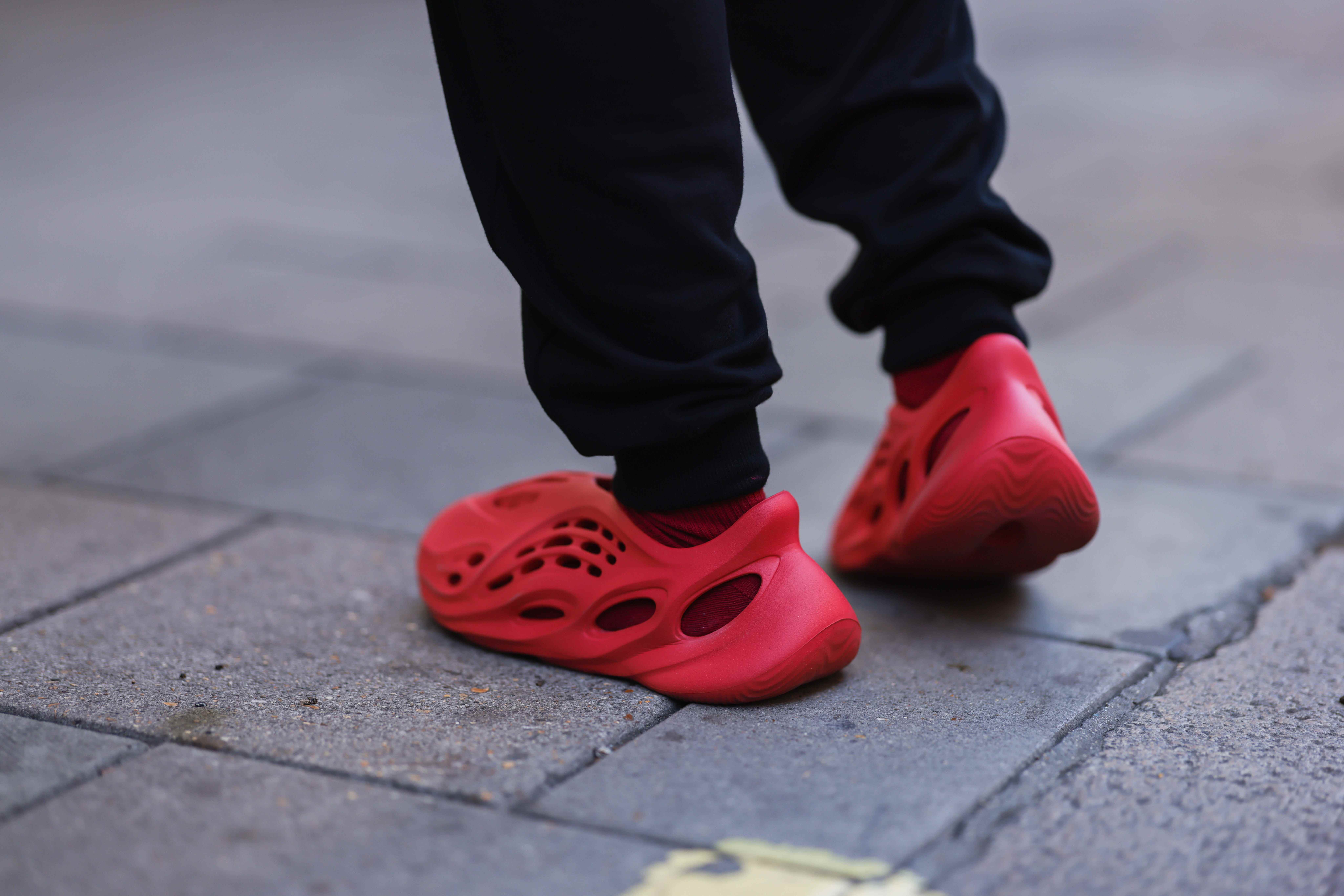 Füße tragen rote Yeezy Adidas Foam Runner Schuhe