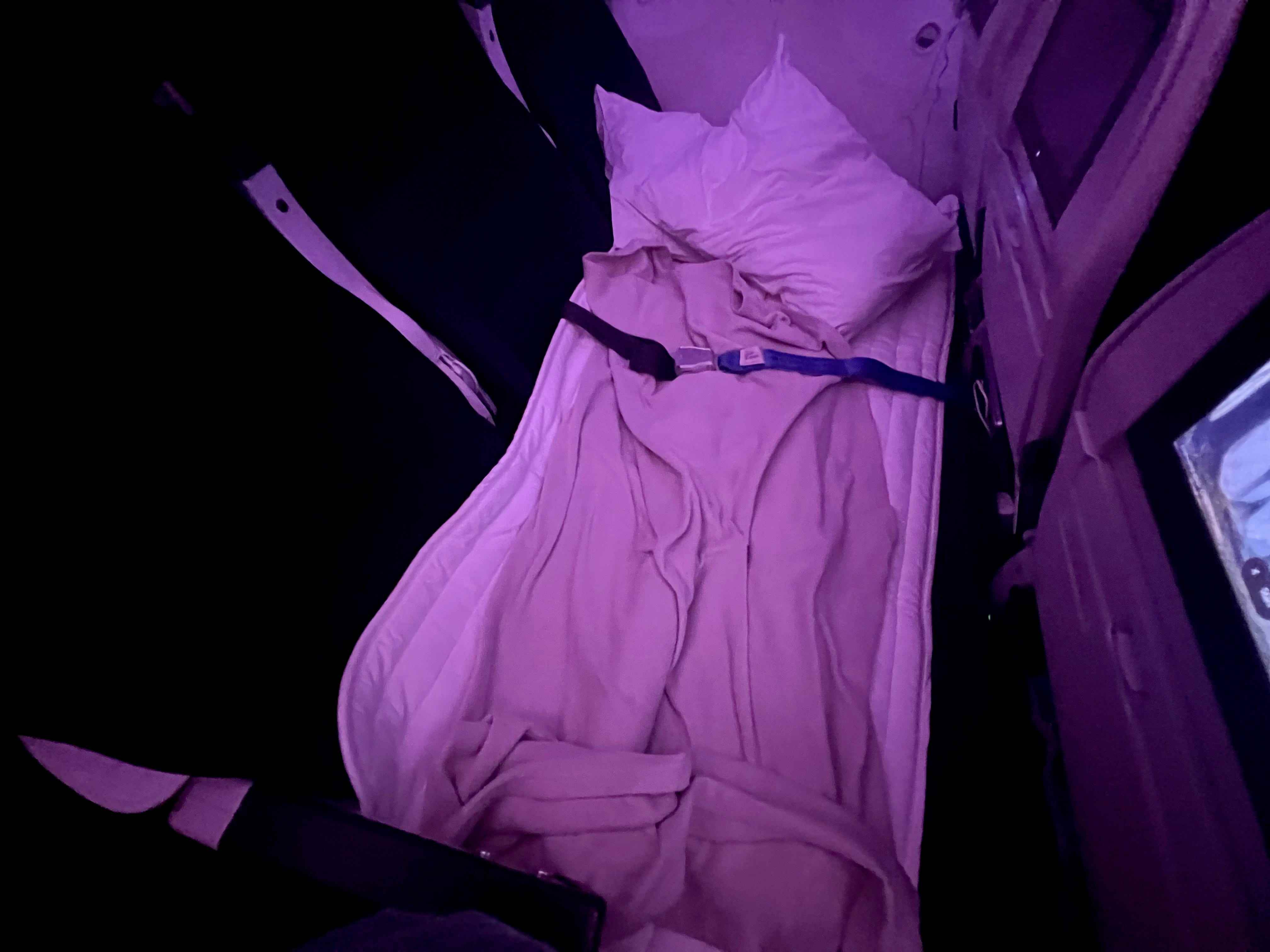 Die Skycouch von Air New Zealand in ihrer Bettform mit Kissen und Decken.