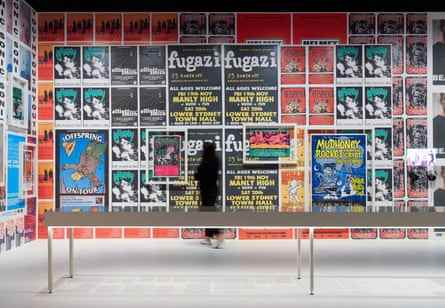 Eine Person inspiziert eine mit Plakaten von Bands wie Fugazi, Mudhoney und The Offspring beklebte Wand