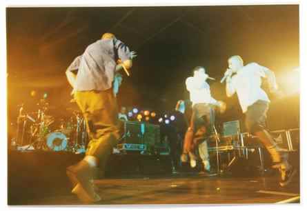 Die Beastie Boys auf der Bühne, mit zwei Mitgliedern, die während ihres Auftritts in die Luft springen