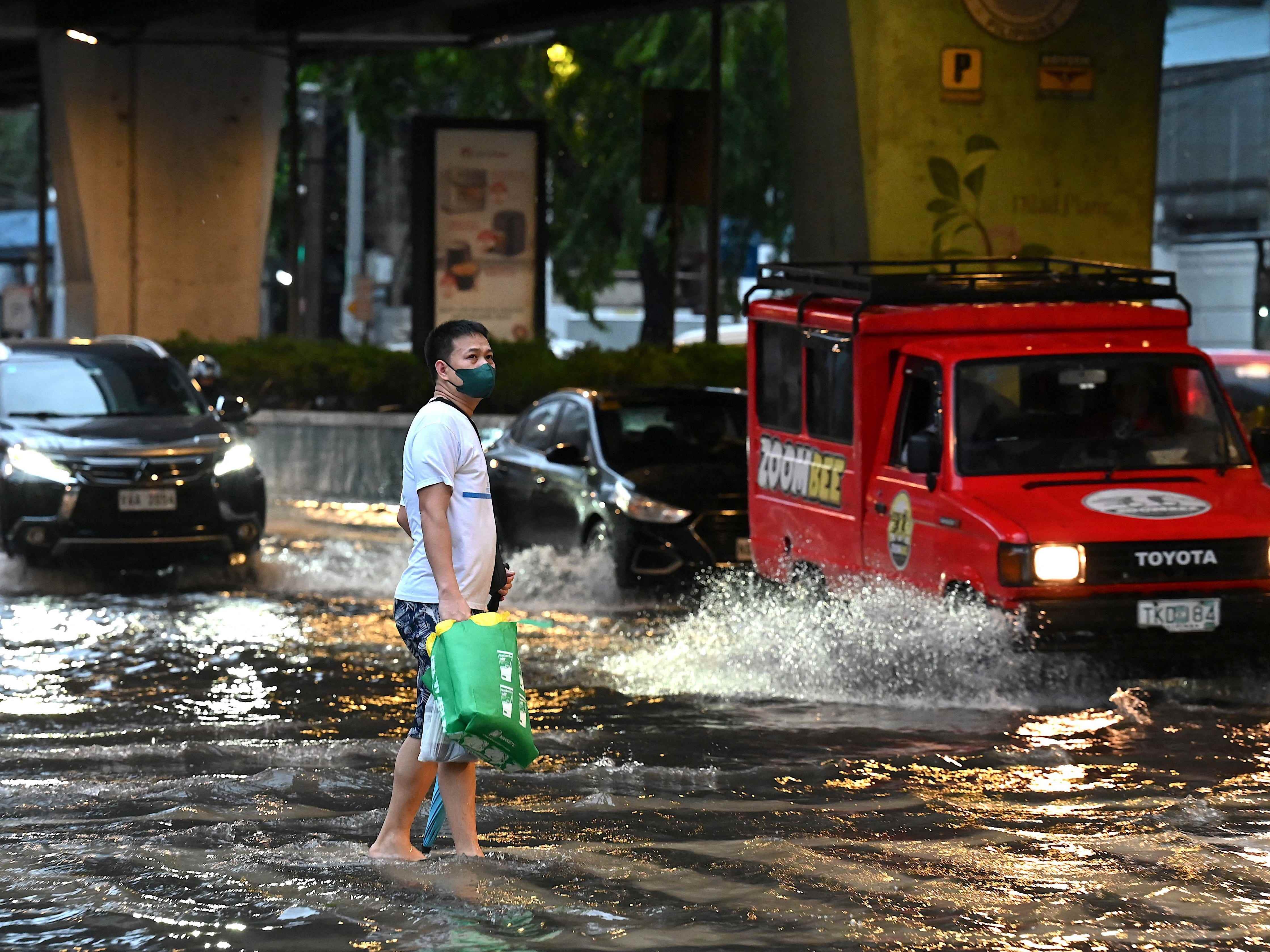 Ein Mann geht am 29. Oktober 2022 nach starken Regenfällen durch den Tropensturm Nalgae in Manila eine überflutete Straße entlang.