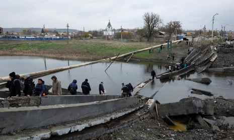 Menschen verlassen und kehren zu ihren Unterkünften zurück, während sie eine zerstörte Brücke überqueren, um Hilfsgüter in der östlichen Donbass-Region von Bachmut, Ukraine, zu sammeln, 30. Oktober.