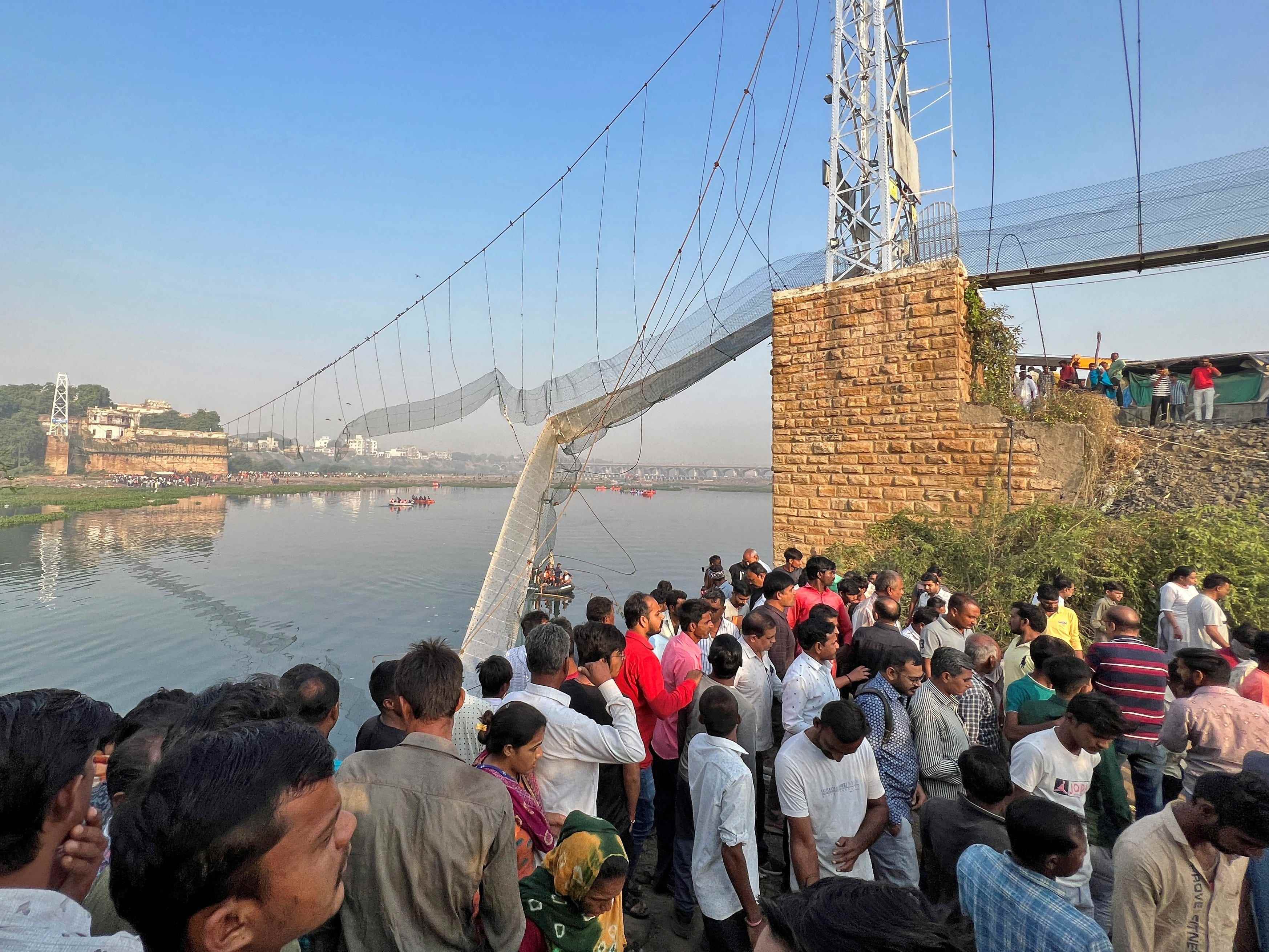 Menschen versammeln sich, während Retter nach Überlebenden suchen, nachdem eine Hängebrücke in der Stadt Morbi eingestürzt ist.
