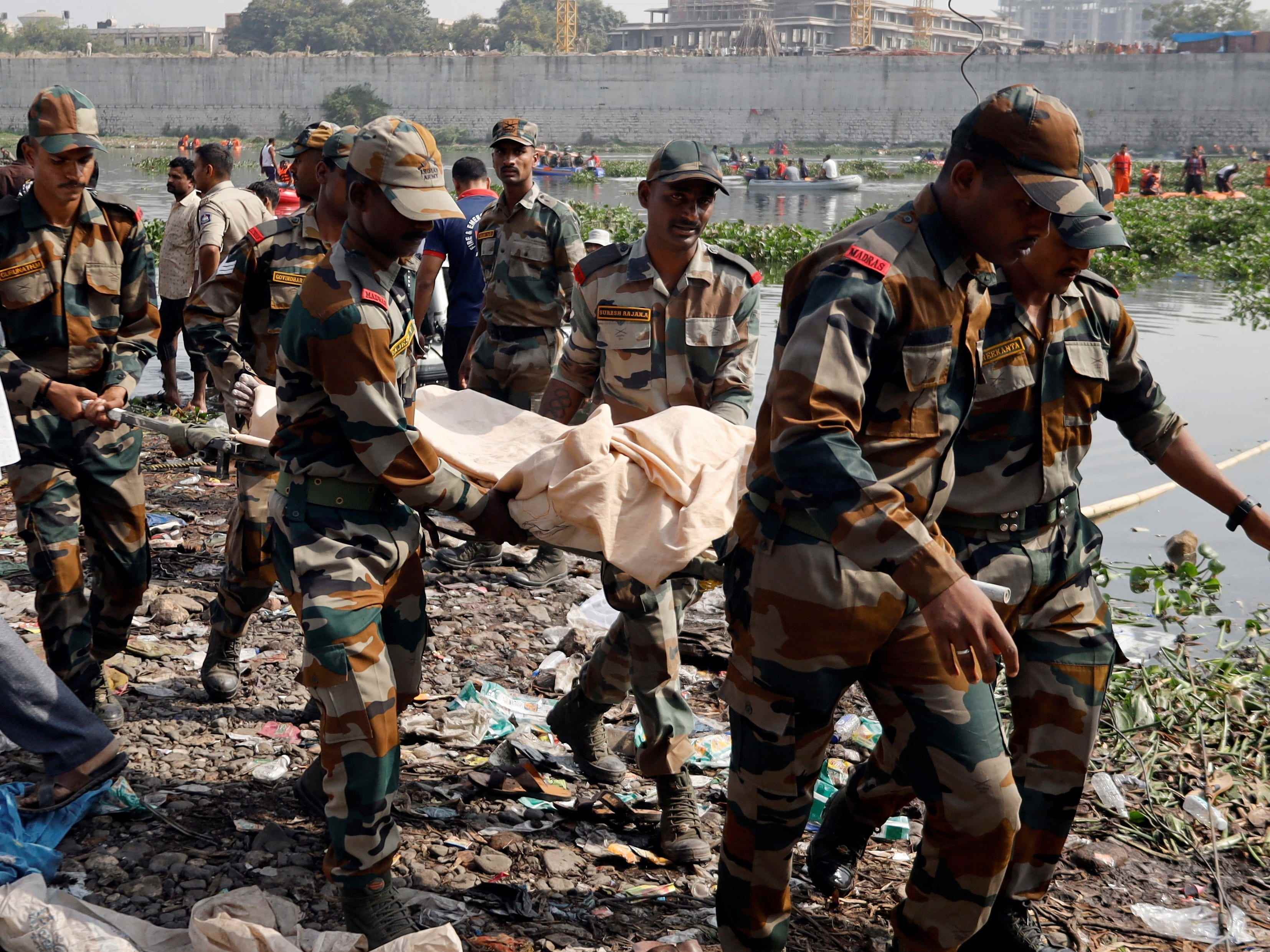 Armeesoldaten tragen die Leiche eines Opfers nach dem Einsturz einer Hängebrücke in Morbi.