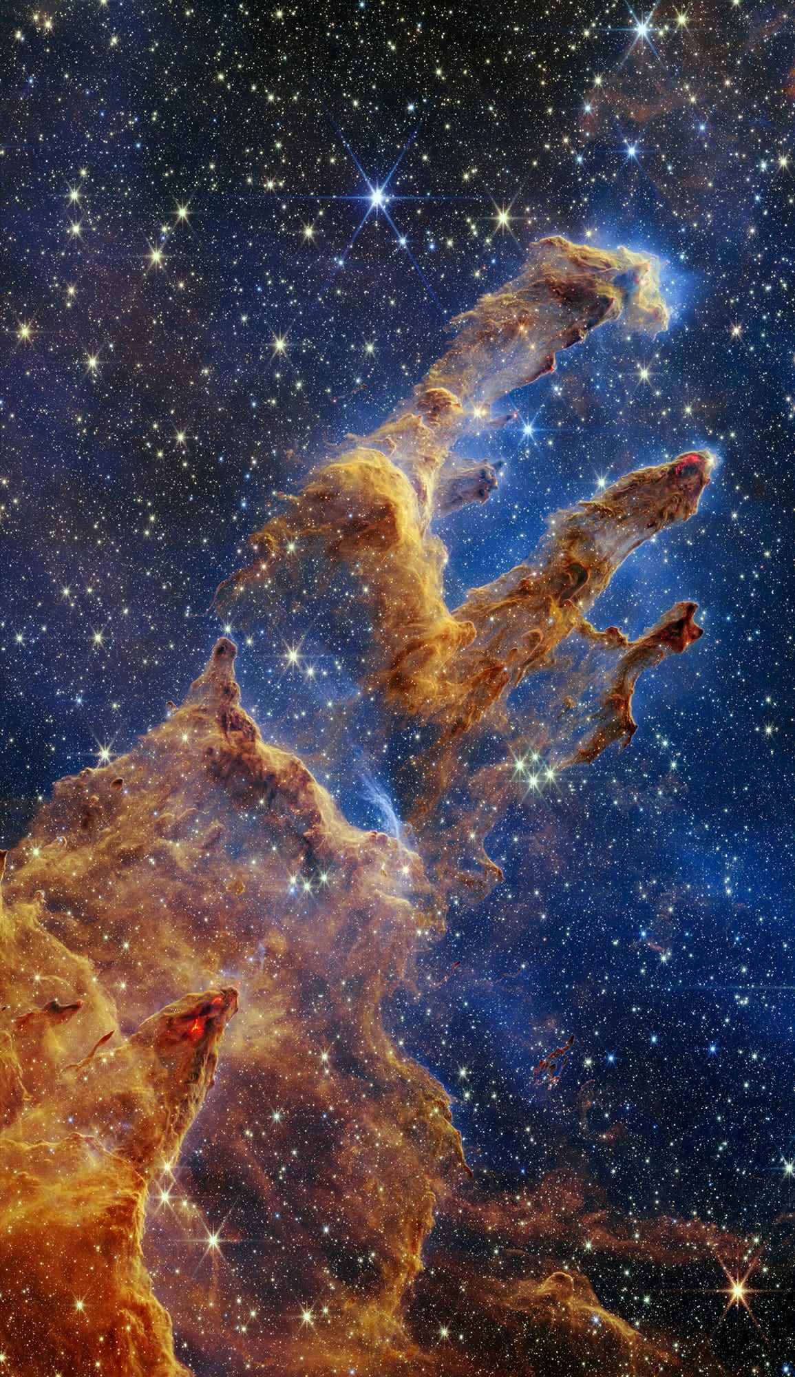 Die Säulen der Schöpfung sind in einem Kaleidoskop aus Farben in der Nahinfrarotlichtansicht des James Webb Space Telescope der NASA hervorgehoben.  Die Säulen sehen aus wie Bögen und Spitzen, die sich aus einer Wüstenlandschaft erheben, sind aber mit halbtransparentem Gas und Staub gefüllt und verändern sich ständig.  Dies ist eine Region, in der sich junge Sterne bilden – oder kaum aus ihren staubigen Kokons geplatzt sind, während sie sich weiter bilden.