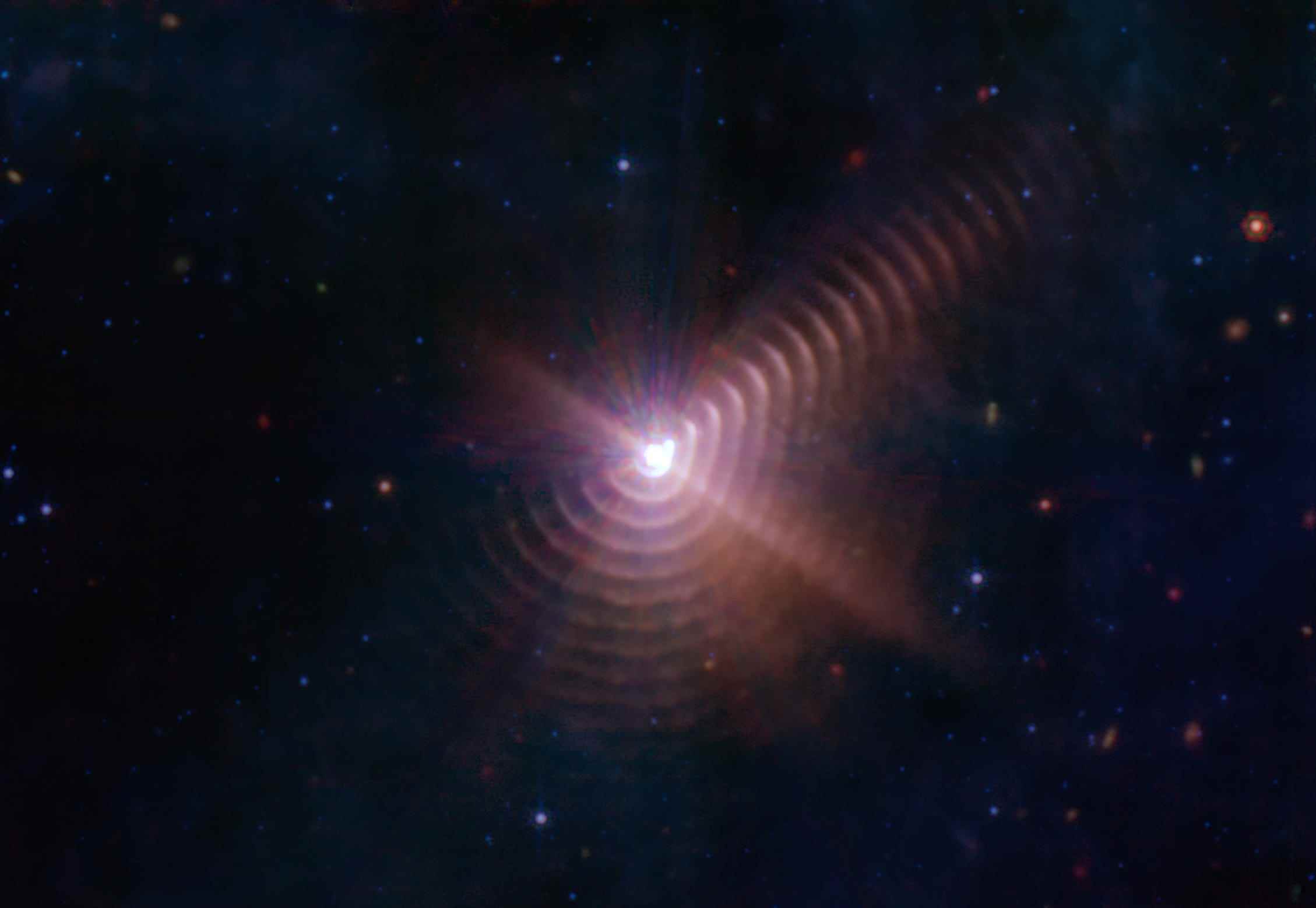 Hüllen aus kosmischem Staub, die durch die Wechselwirkung von Doppelsternen entstanden sind, erscheinen wie Baumringe um Wolf-Rayet 140.