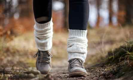 Frau zu Fuß auf Fußweg im Wald.  Gestrickte Beinlinge am Wanderschuh