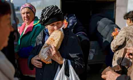 Eine Frau erhält einen Laib Brot, der am 3. November in einem Dorf nahe der Frontlinie im Süden von Mykolajiw, Ukraine, verteilt wird.