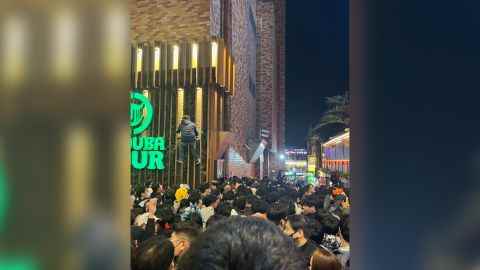 Ein Mann wird am 29. Oktober in Itaewon, Seoul, gesehen, wie er ein Gebäude erklimmt, um der Menge zu entkommen. 