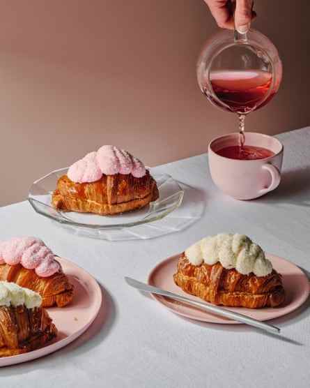 Fingerbrötchen-Croissants, dh mit Kokosglasur überzogene und mit Erdbeermarmelade gefüllte Croissants, angerichtet auf rosafarbenen Tellern.