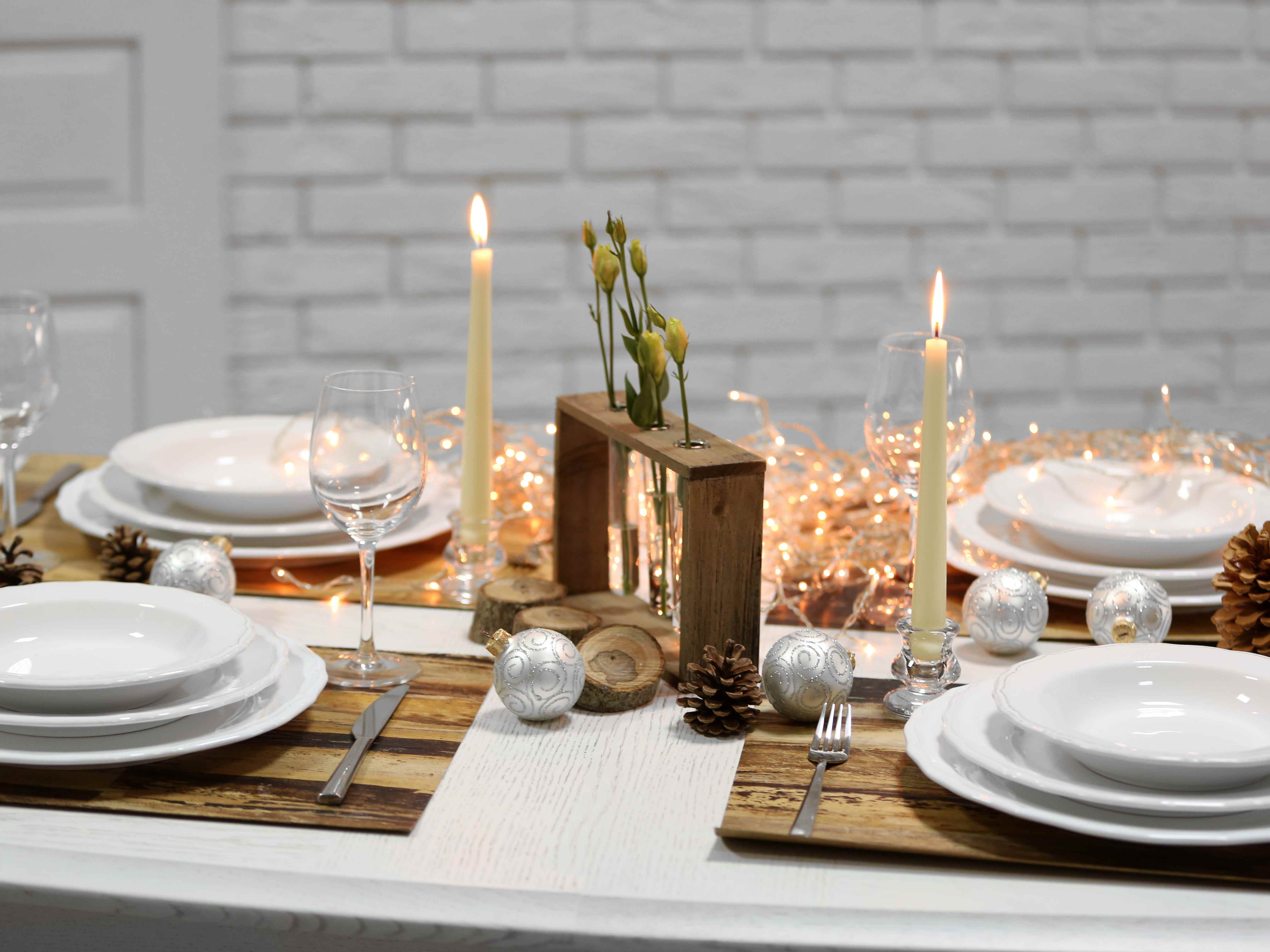 Tischdekoration mit Lichterketten und Kerzen, Tischsets aus Holzimitat, weißen Tellern und Besteck