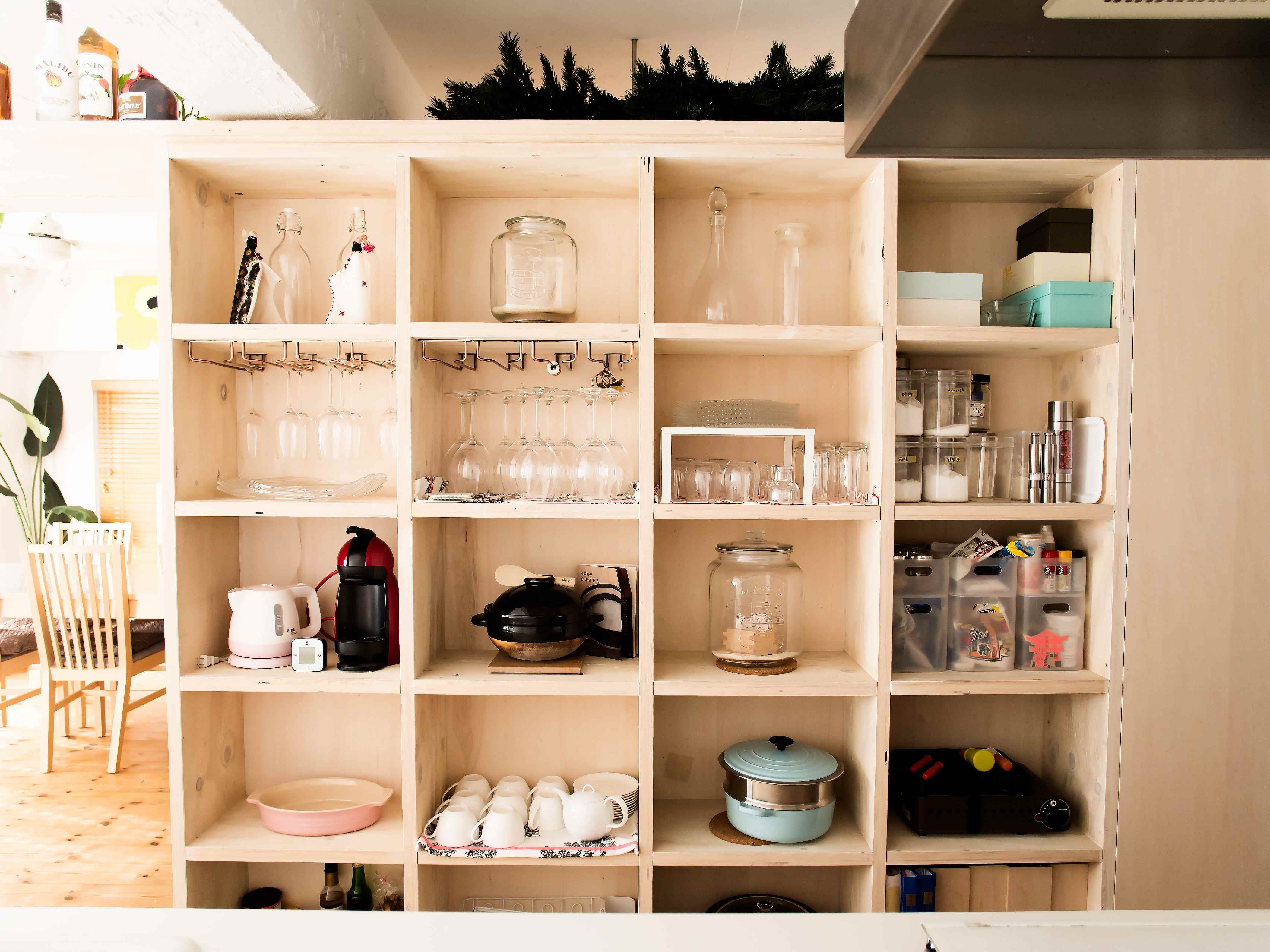 Mit Gläsern, Töpfen und Geschirr gefüllte Holzschränke in einer Küche