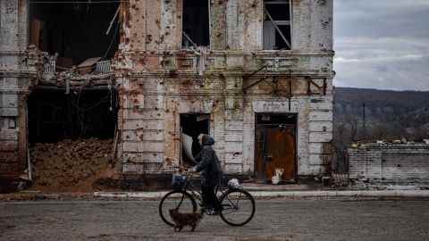 Eine Frau fährt am 3. November 2022 inmitten der russischen Invasion in der Ukraine mit dem Fahrrad an einem beschädigten Gebäude in der Stadt Kupjansk in der Region Charkiw vorbei.