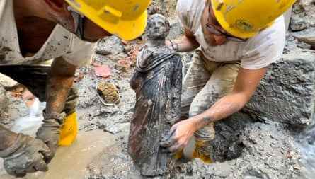 Zwei Archäologen halten eine Statue eines Jungen.