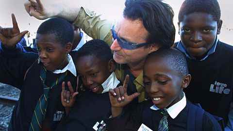Der irische Rocker Bono, Leadsänger von U2, posiert im Mai 2002 mit Schulkindern im Township Soweto außerhalb von Johannesburg, Südafrika. 