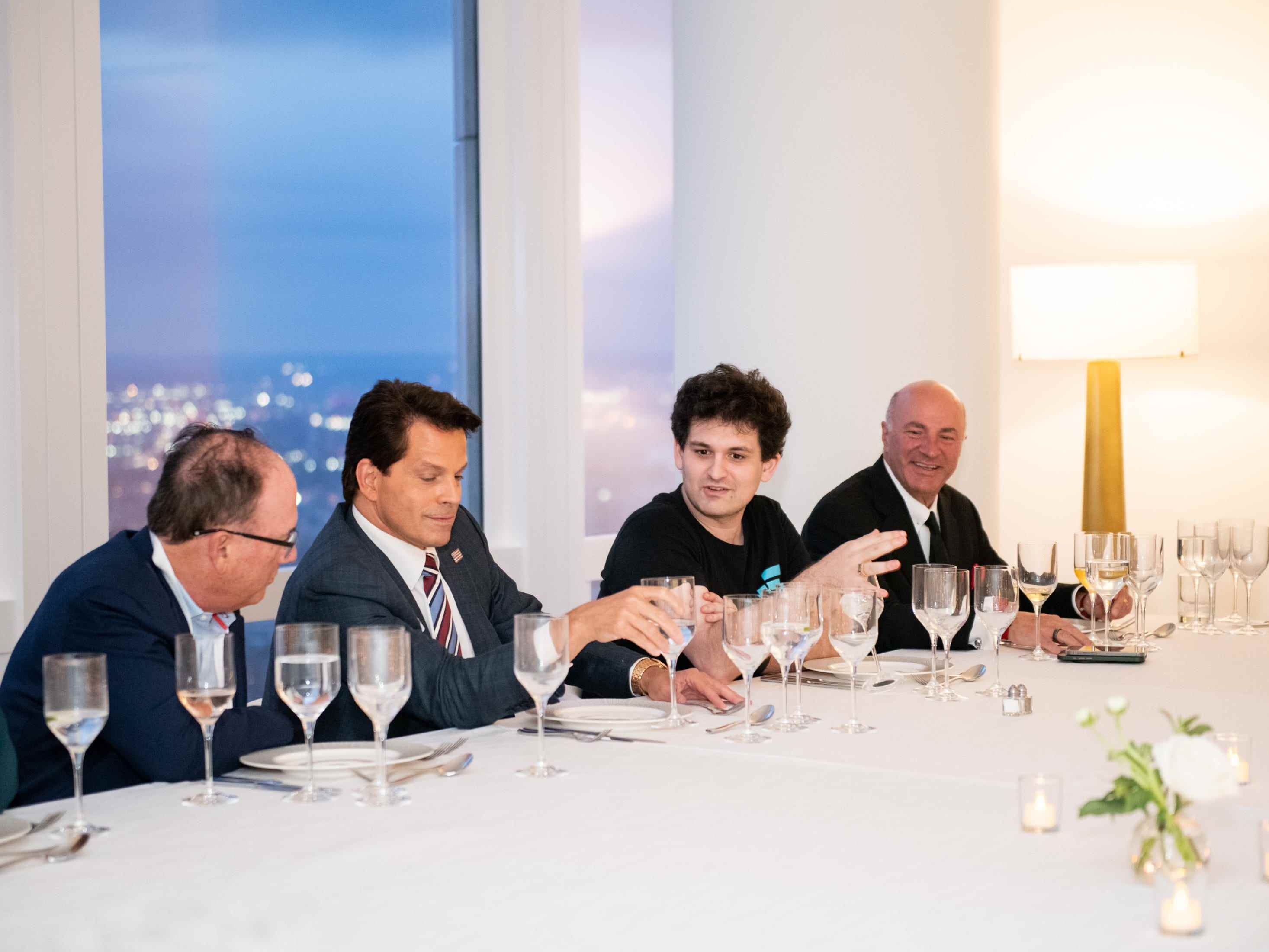 Sam Bankman-Fried sitzt an einem langen weißen Tisch beim Abendessen mit Anthony Scaramucci und dem Shark-Tank-Investor Kevin O'Leary.